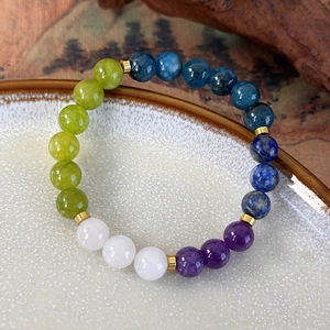 Detailed view of colorful natural stone beads and golden spacers on a ceramic plate