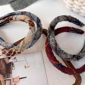 Set of four handmade tweed knit headbands in vibrant colors on a wooden display tray