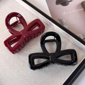 Detail of burgundy and black bow hair claws in glossy acrylic with strong metal springs