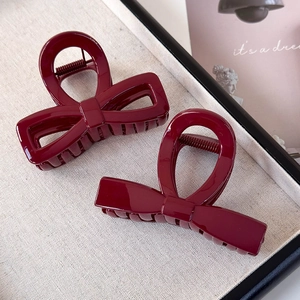 Close-up of wine red bow-shaped hair claws with glossy finish and metal springs