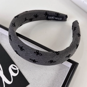 Close-up of gray knitted headband with black bows and a sewn HAND MADE label