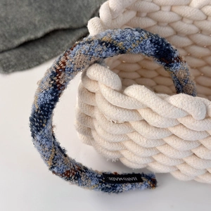 Close-up of handmade plaid tweed headband in blue and yellow on woven cotton basket