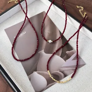 Detailed view of red faceted bead necklaces with pearl and gold accents on dark wood