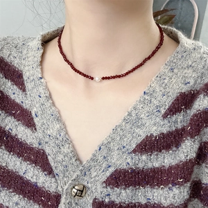 Detail of red beaded choker necklace with a central white pearl on a female model