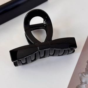 Detail view of polished black bow-shaped hair claw clip with glossy resin finish