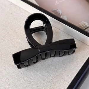 Close-up of a glossy black bow hair claw clip with polished finish and sturdy spring