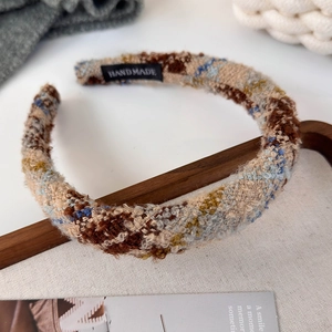 Detail of multi-color wool tweed headband with handmade label on warm canvas