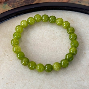 Detailed macro view of vibrant green beaded bracelet on natural fiber background
