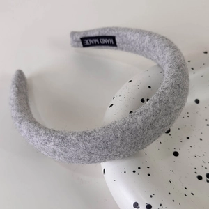 Detail of grey padded headband featuring a 'HAND MADE' label on the inner fabric