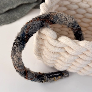 Close-up of textured blue tweed headband featuring a black Handmade textile label