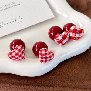 Red bead and gingham fabric heart earrings set on a white ceramic plate for a retro look