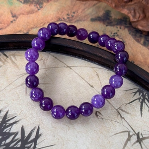 Detailed close-up of natural purple amethyst beads on a zen-style dark bamboo background
