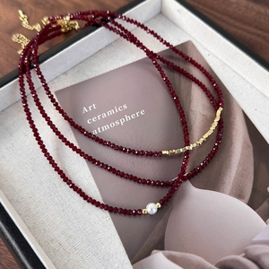 Detail of burgundy faceted beads and white pearl necklace with gold-plated chain