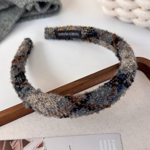 Close-up of a tweed checkered headband featuring a vintage woven texture and handmade tag