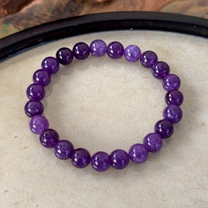 Macro detail of natural purple amethyst beaded bracelet on a textured display tray