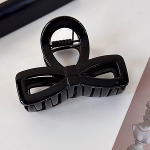 Detailed view of the glossy black bow hair claw clip with a sleek resin finish