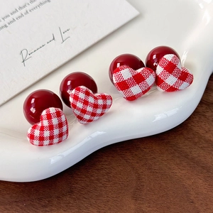 Detailed view of heart-shaped earrings with red and white plaid fabric on a ceramic tray