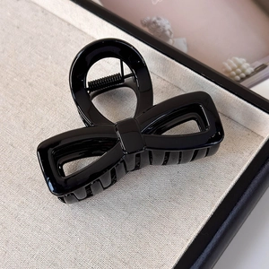 Close-up of glossy black bow hair claw clip with strong metal spring and teeth