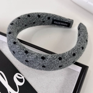 Detailed view of grey polka dot headband fabric with black handmade woven label