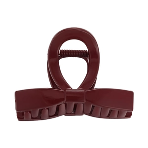 Macro detail of burgundy bow hair claw clip featuring high-gloss finish and metal spring