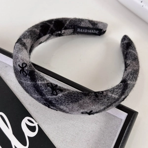 Macro detail of thick grey knitted headband featuring handmade label and wool texture