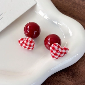 Macro shot of red plaid fabric heart earrings with polished dark red resin beads on a tray