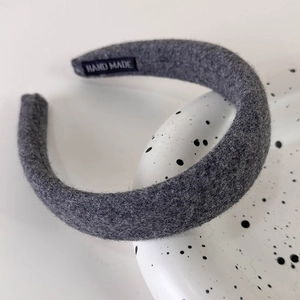 Detail of dark grey felt headband with textured wool and a Hand Made woven label
