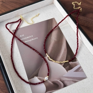 Detail of red faceted bead necklaces with pearl accent and golden metal charms