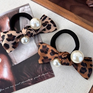 Modische Haargummis mit Leoparden-Schleife und weißen Perlen auf Vintage-Hintergrund