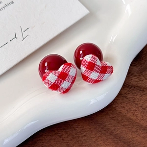 Macro view of red and white plaid fabric heart earrings with glossy deep red beads