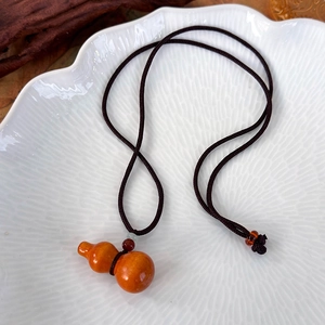 Vue détaillée d'un pendentif gourde en bois sculpté avec un collier en corde tressée