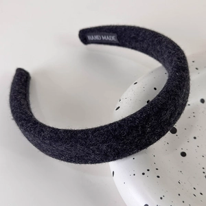 Close-up of thick black plush headband with hand made label and fuzzy wool texture