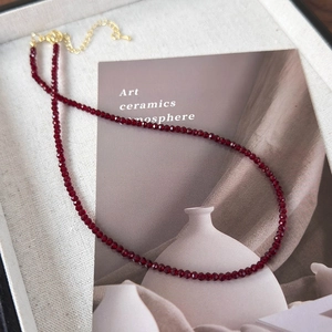 Close-up of deep red faceted pearl necklace with gold extension chain in gift box