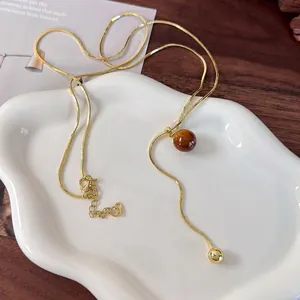 Maillard tiger eye stone snake chain necklace with gold beads on white ceramic tray