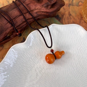 Détail du pendentif gourde en bois sur collier en corde tressée avec perles colorées
