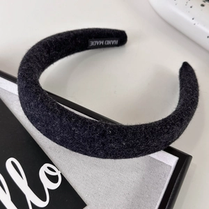 Detail of black handmade knitted headband showing thick wool texture and craft label