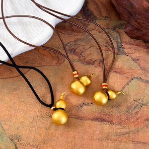 Traditional gold gourd pendants with adjustable cords on artistic landscape background