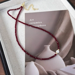 Detailed macro view of dark red faceted bead necklace with a white pearl and gold clasp