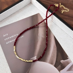 Detail of red faceted bead necklace with gold square accents and adjustable chain