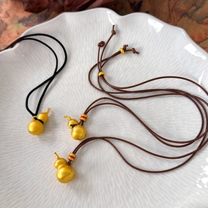 Macro detail of three frosted gold gourd pendants on ceramic plate with colored rings