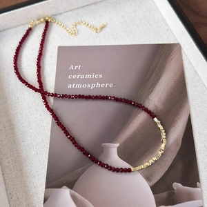 Detail of red beaded necklace with gold metal cubes inside an elegant jewelry box