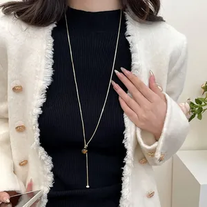 Detail of a vintage gold tiger eye stone Y-shaped sweater necklace on a model