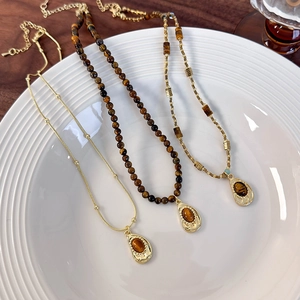 Detailed view of tiger eye stone necklaces with drop pendants on a ceramic plate