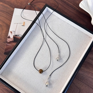 Détail du collier en cordon de cuir avec pierre œil de tigre et pendentifs argentés