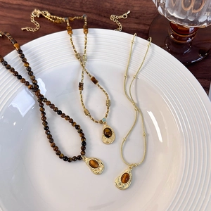 Three vintage tiger eye necklaces in gold plating displayed on a white plate
