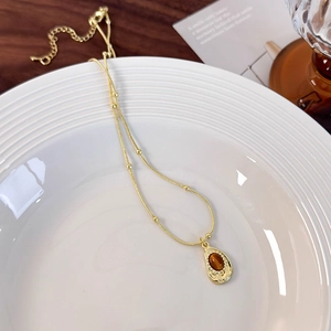 Macro detail of tiger eye pendant on gold chain with beads in a ceramic tray