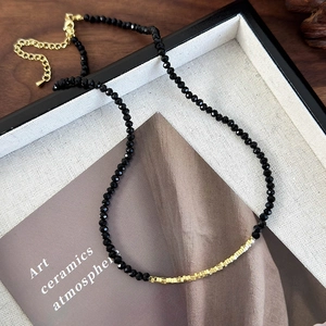 Detailed macro view of minimalist black faceted bead necklace with gold accent cubes