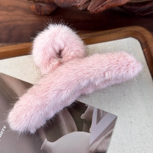 Dettaglio di un fermaglio per capelli in peluche rosa su vassoio di legno con finta pelliccia