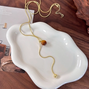 Macro detail of a golden tiger eye stone pendant on a long Y-shaped snake chain necklace