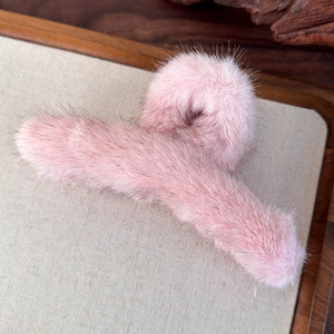 Dettaglio di un fermaglio per capelli in peluche rosa con finitura in finta pelliccia